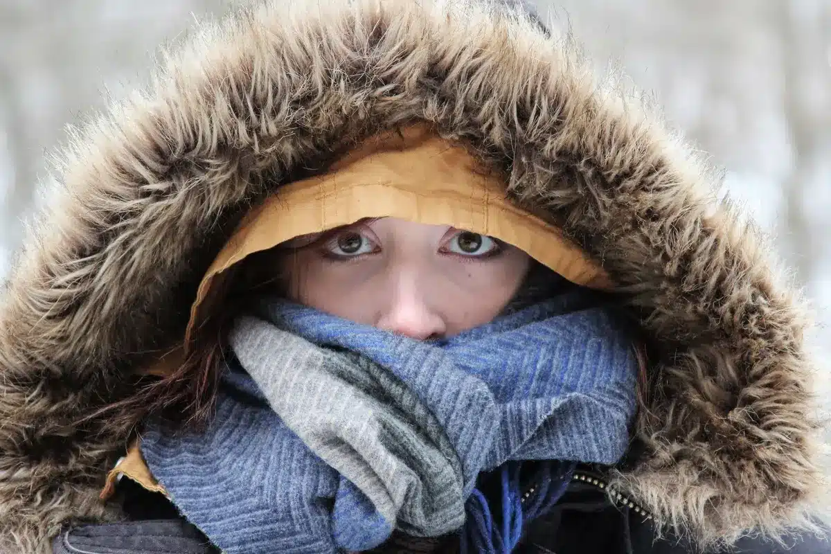 Persona abrigada con varias capas de ropa, gorro y protección en manos y pies