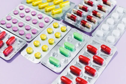 Medicamentos y cajas en estante de farmacia, mano de cliente alcanzando un producto