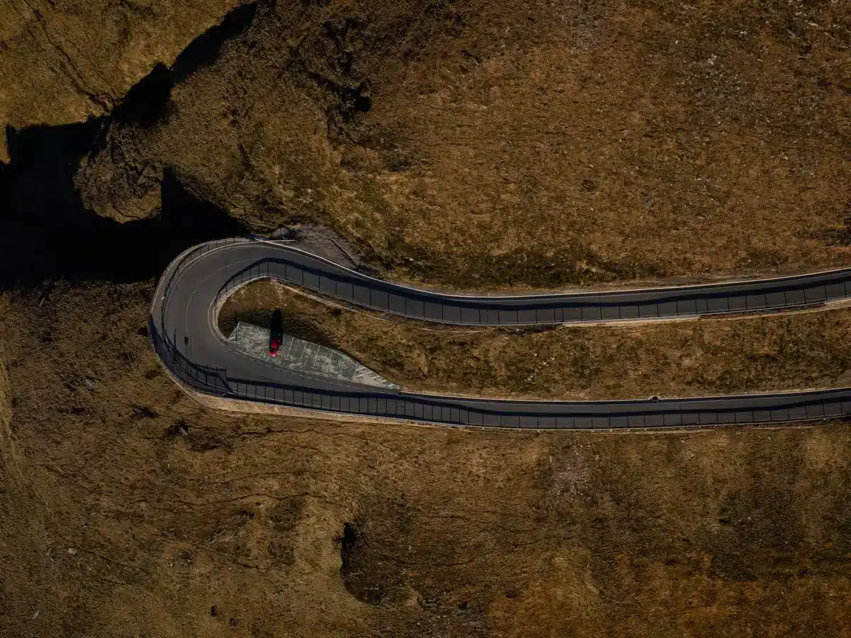 Curva cerrada en ruta de montaña con pronunciadas pendientes y barranco profundo.