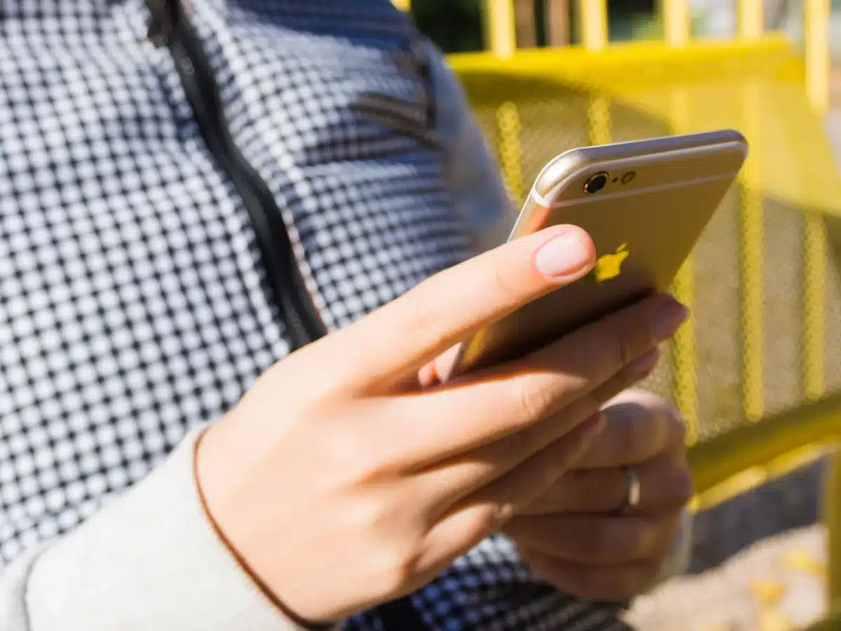 Persona revisando el teléfono con gesto de ansiedad y preocupación.