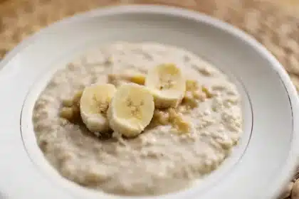 Bol de avena con nueces y manos sirviendo una porción sobre una mesa de cocina