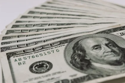 Billetes de peso y dólar sobre escritorio con gráficos financieros de fondo