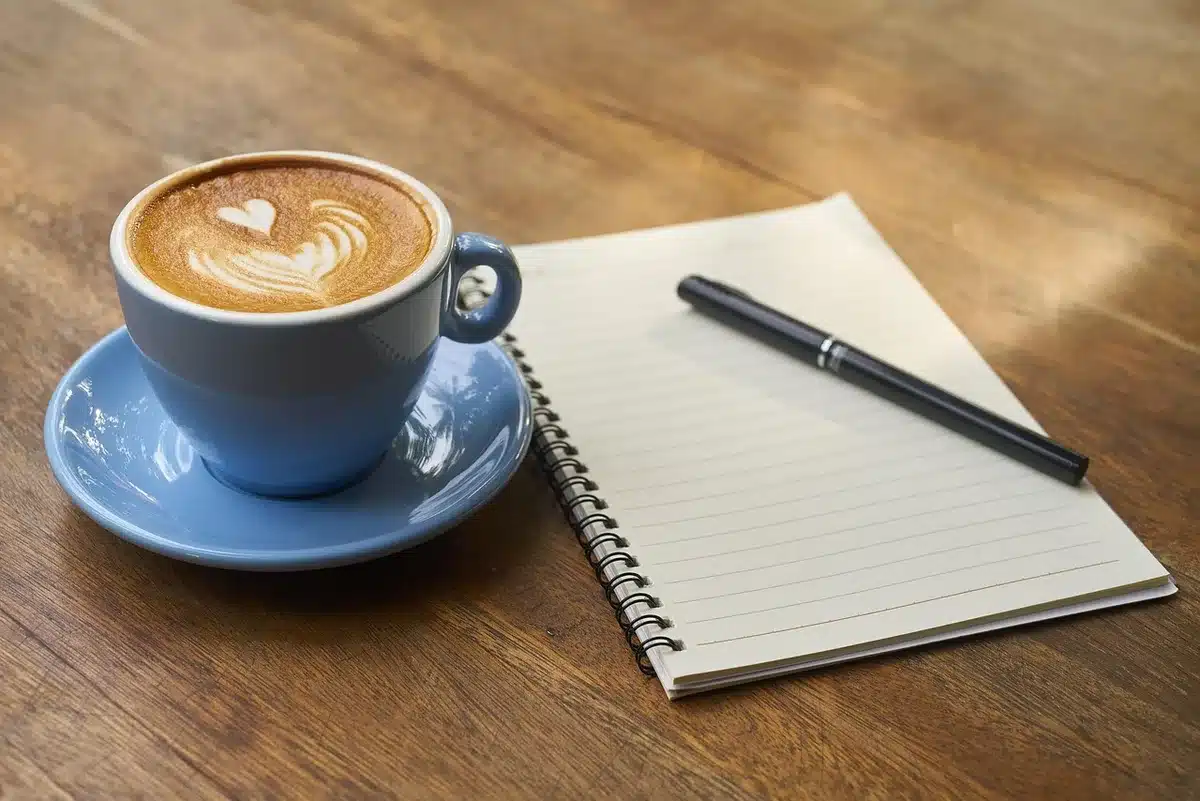 Persona tomando notas en un cuaderno en una cafetería