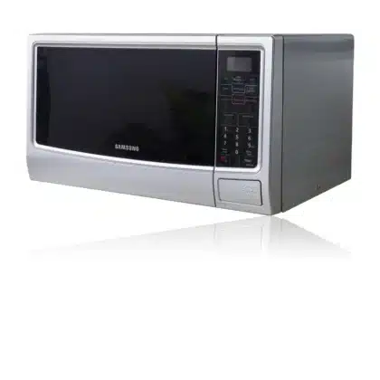 Manos anónimas colocando un recipiente en el microondas de una cocina moderna