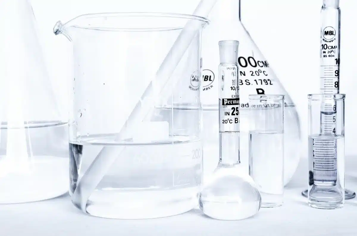 Manos con guantes junto a tubos de ensayo y equipo de laboratorio que sugiere edición genética