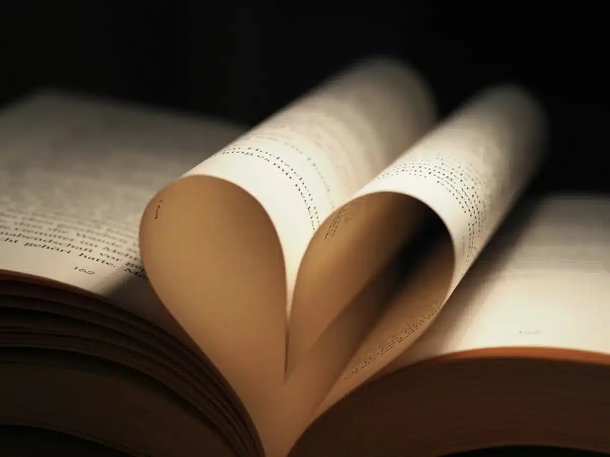 Manos sosteniendo un libro gastado a la luz suave, simbolizando aceptación de la falta