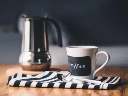 Agenda abierta con una taza de café y un teléfono en modo silencio sobre una mesa