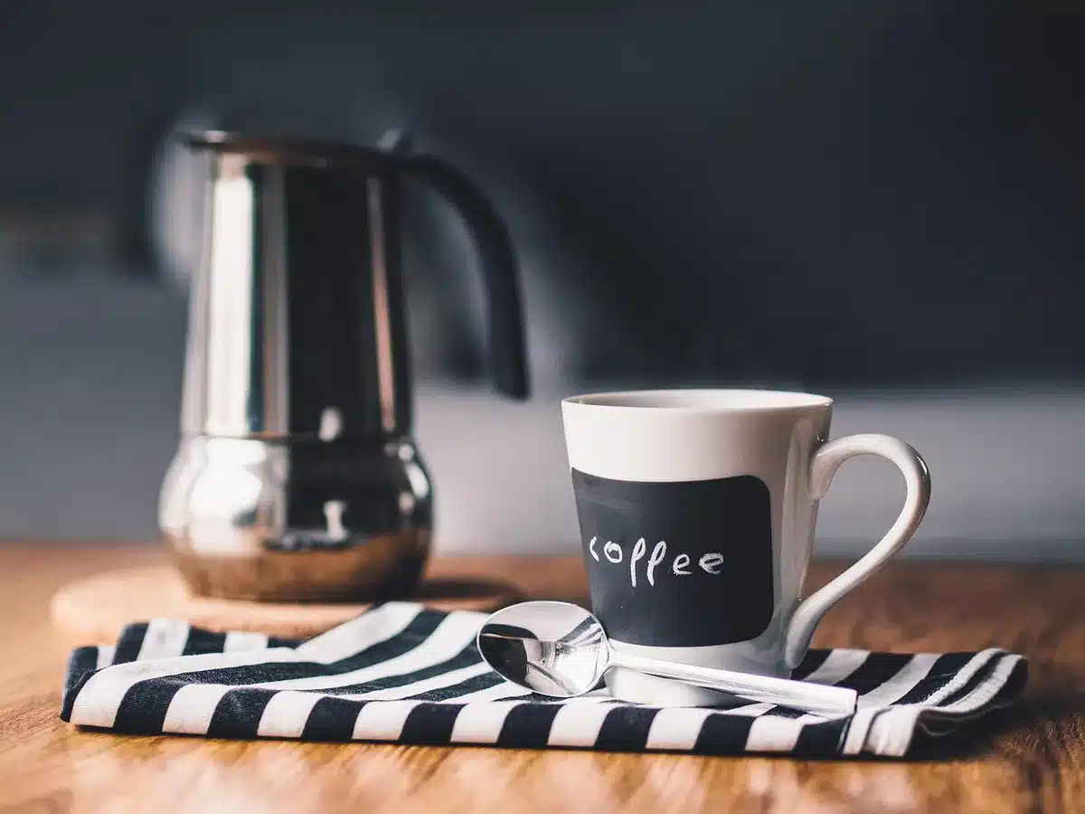 Agenda abierta con una taza de café y un teléfono en modo silencio sobre una mesa