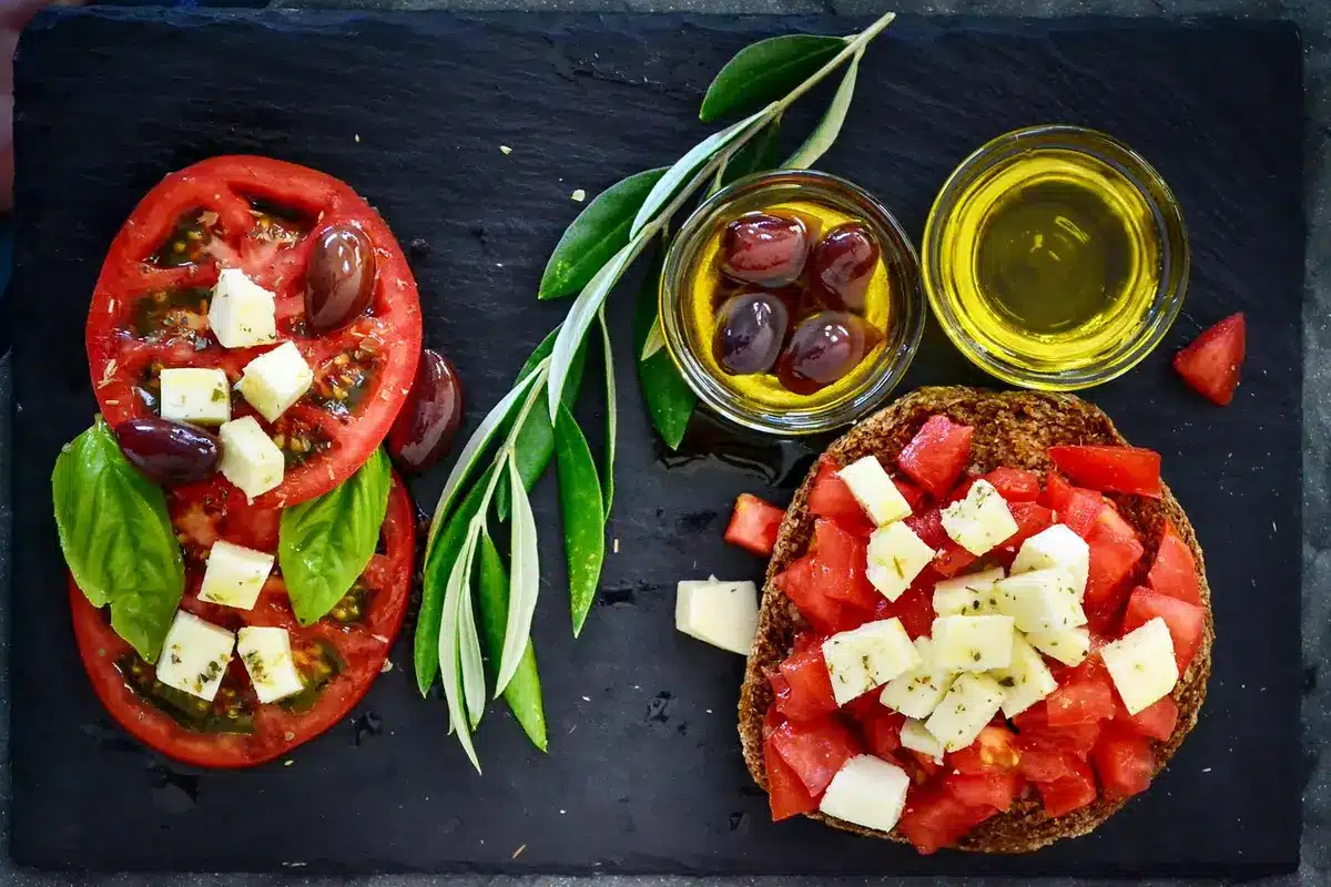 Variedad de verduras, pescado y aceite de oliva sobre mesa, representación dieta mediterránea